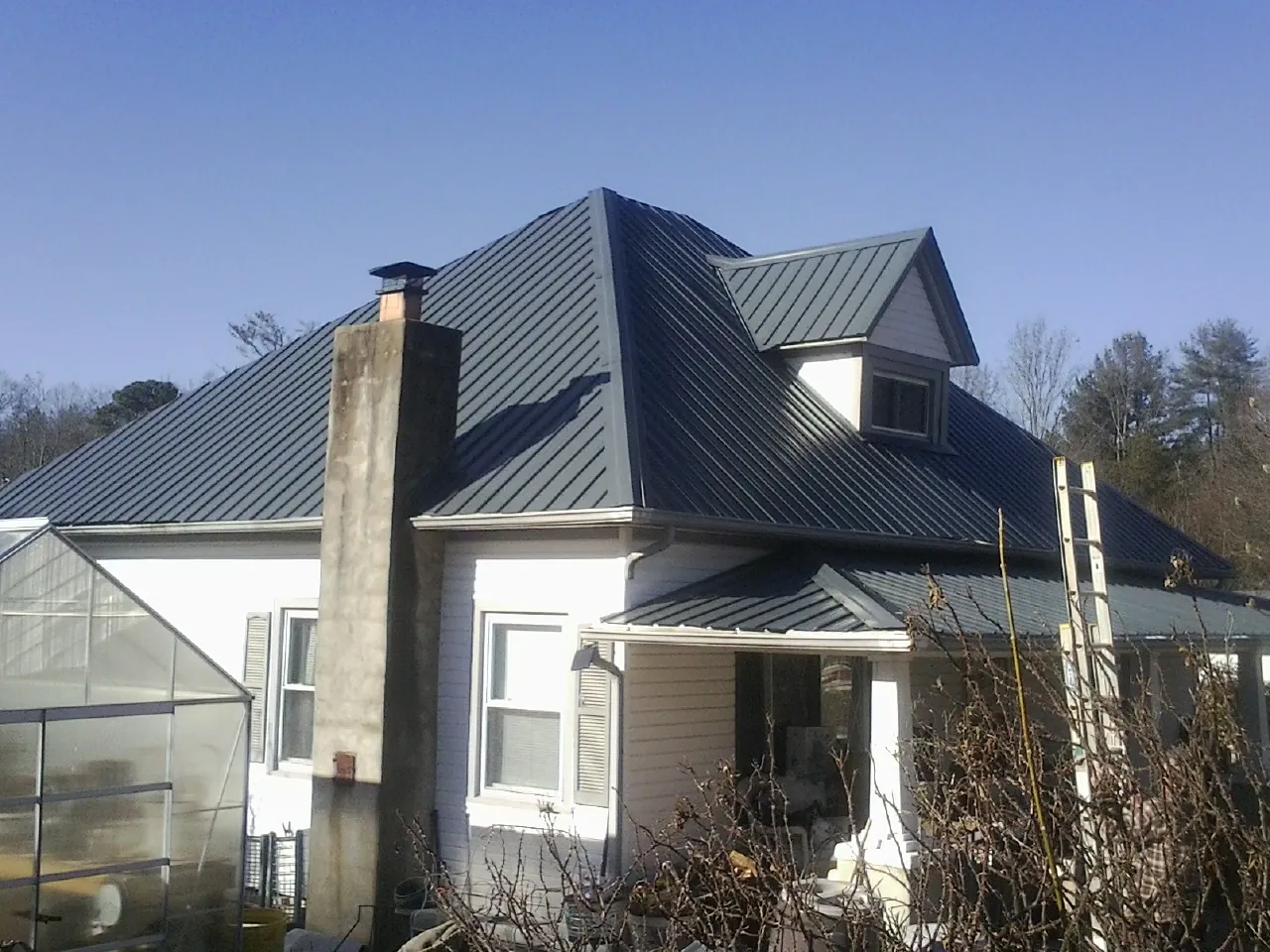 Dark blue standing seam metal roof on a white farmhouse with dormer — Slate & Tile Roof Repair by Roofing Brothers in Fort Plain