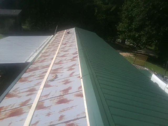 Old rusted panels beside newly installed green metal roofing — Wind Damage Roof Repair by Roofing Brothers in Fort Plain