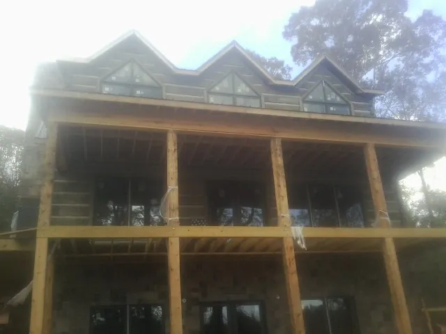 Dormers and porch framing on a large log home under construction — Roof Coating work by our crew in Fort Plain
