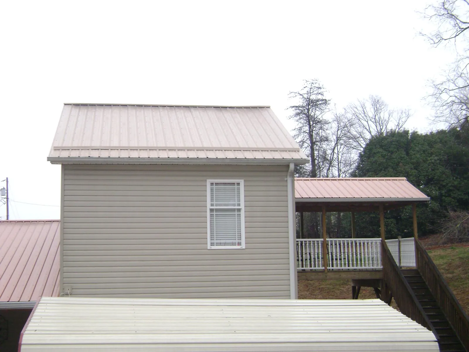 Tan metal roofs on a two story addition and attached porch, from a Roof Replacement job in Fort Plain