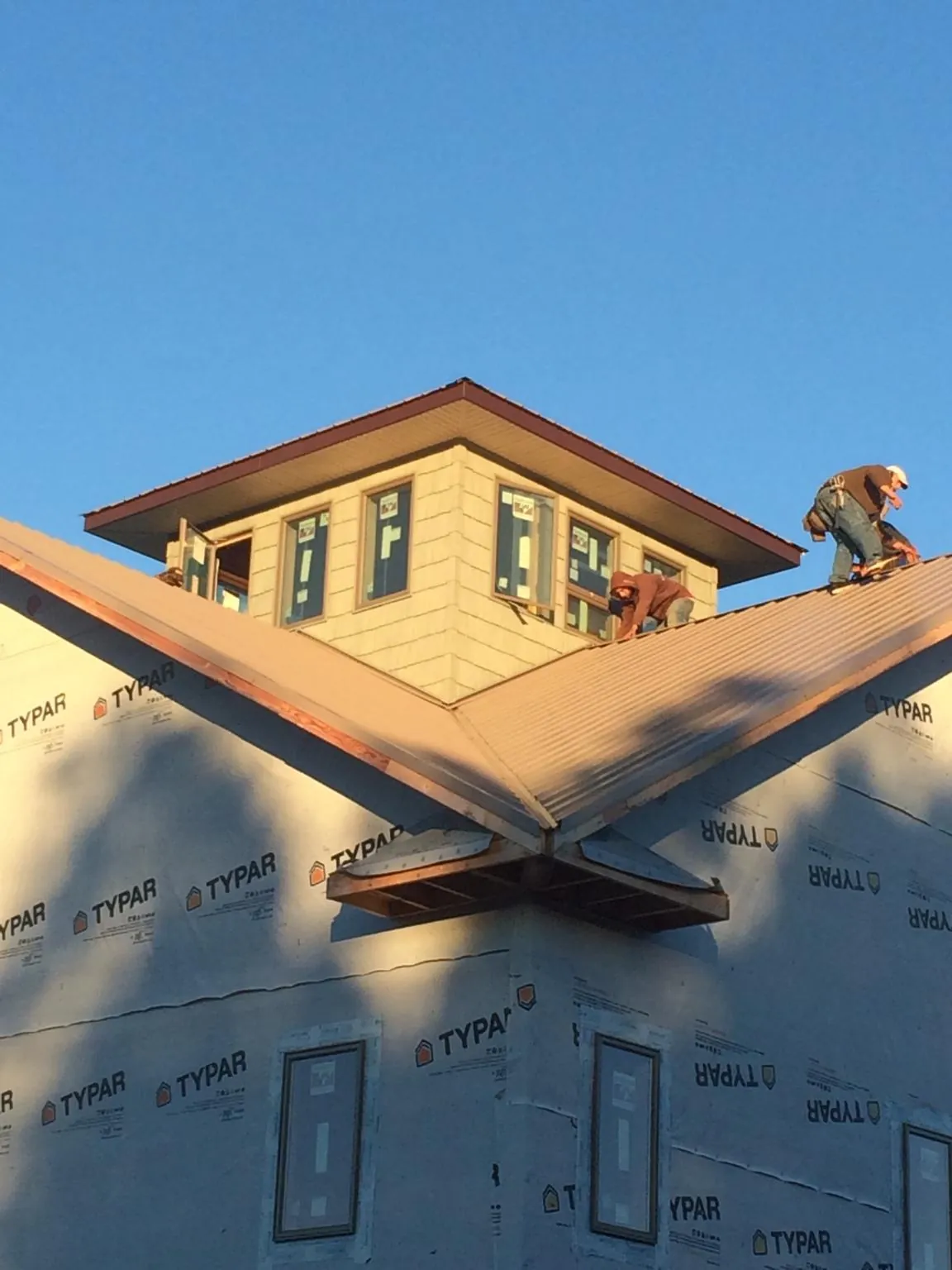 Roofers working around a rooftop cupola on a new metal roof at sunset — Roof Waterproofing in Fort Plain by Roofing Brothers